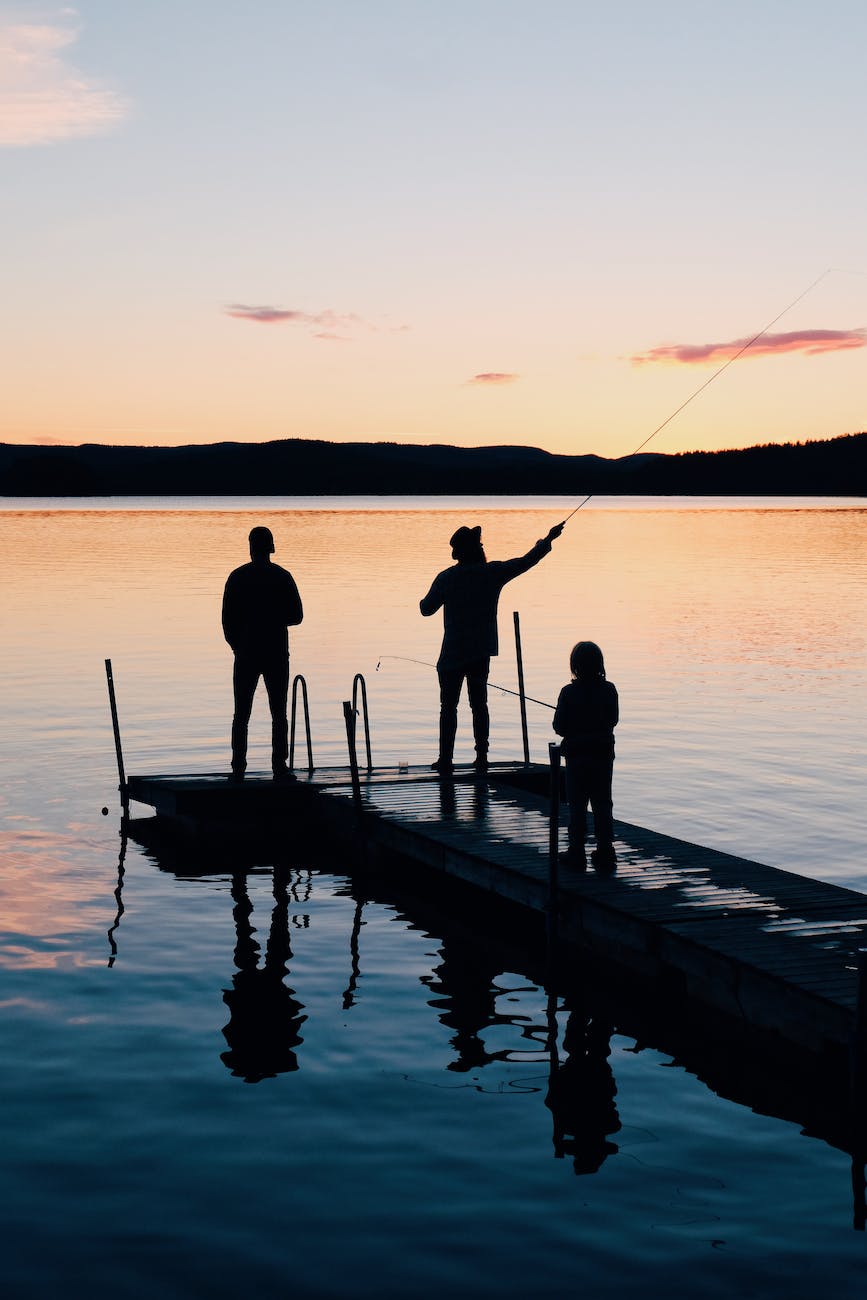 three people on a wooden fishing docks